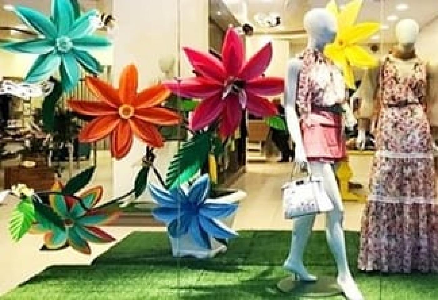 vitrine com flores na frente e manequins de roupas femininas. #paratodosverem