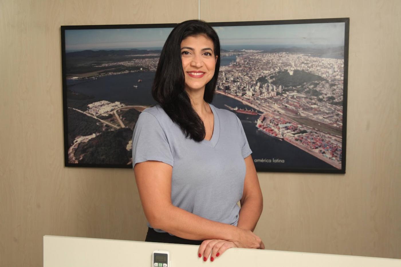 servidora posa na frente de quadro com foto da Cidade #paratodosverem