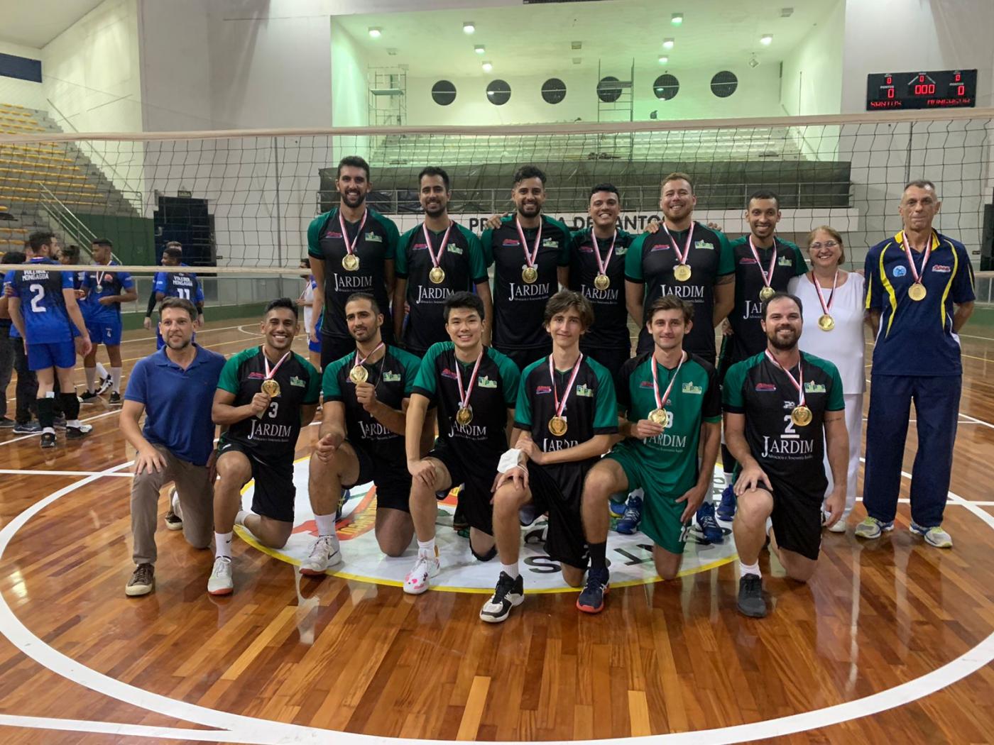 Equipe de vôlei masculino posa para foto na quadra com medalha #paratodosverem