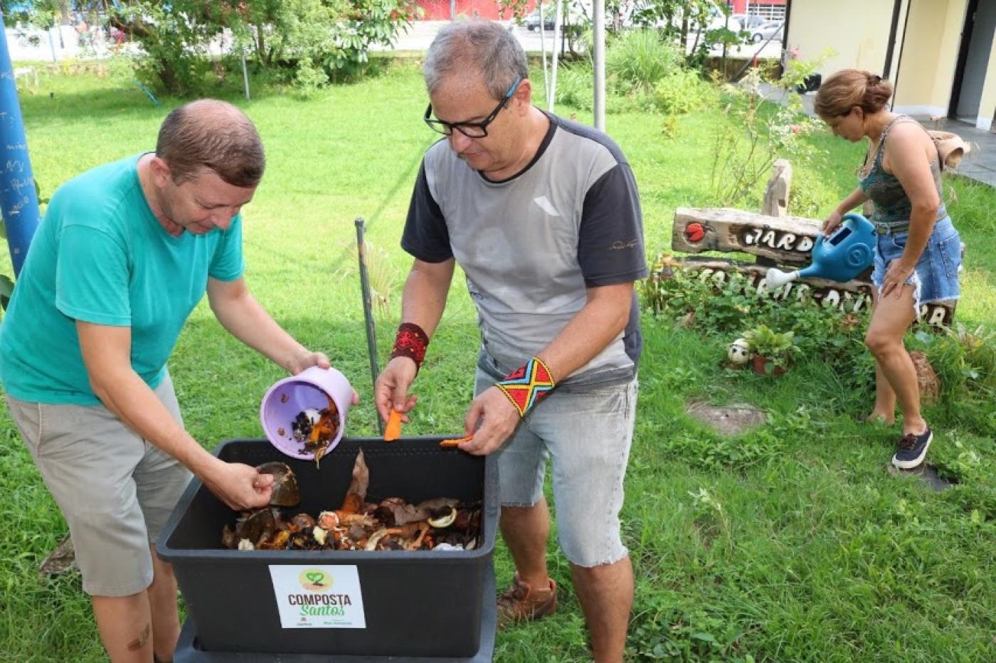 dois homens colocam material em composteira #paratodosverem 