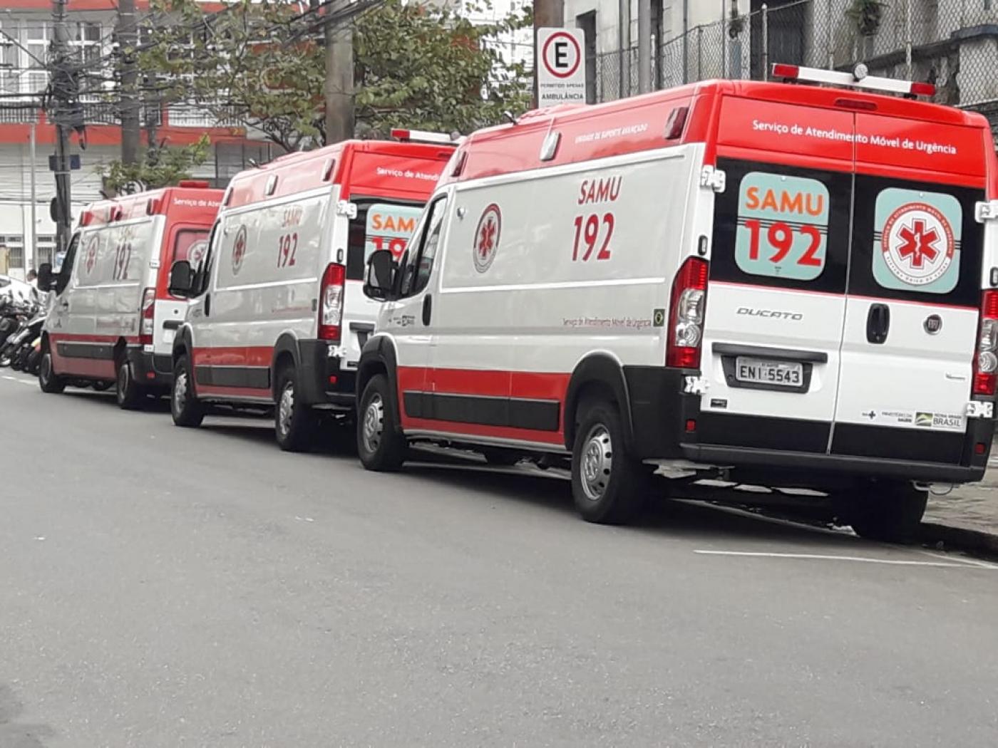 Três ambulâncias estacionados em rua. #Pracegover