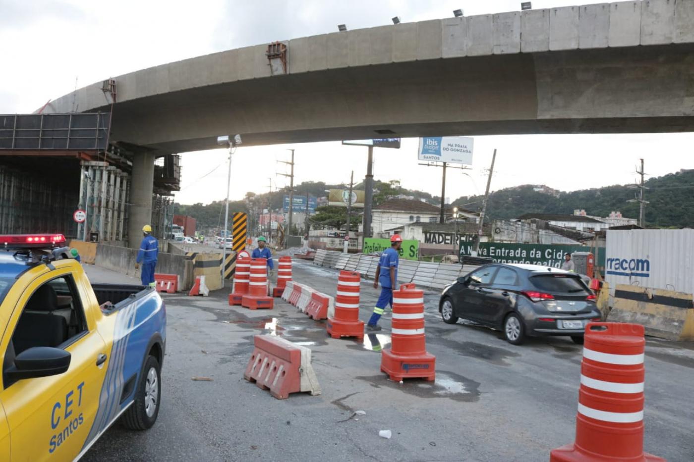 #pracegover Com carro da CET em primeiro plano, foto mostra veículo de passeio trafegando sob o viaduto 