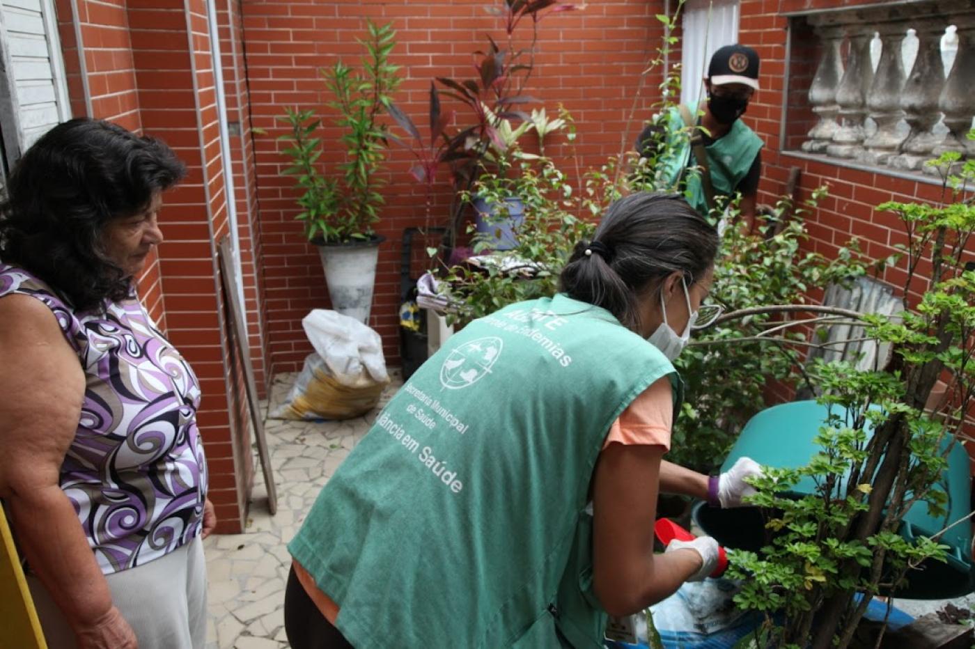 agente verifica vasos de plantas em casa #paratodosverem