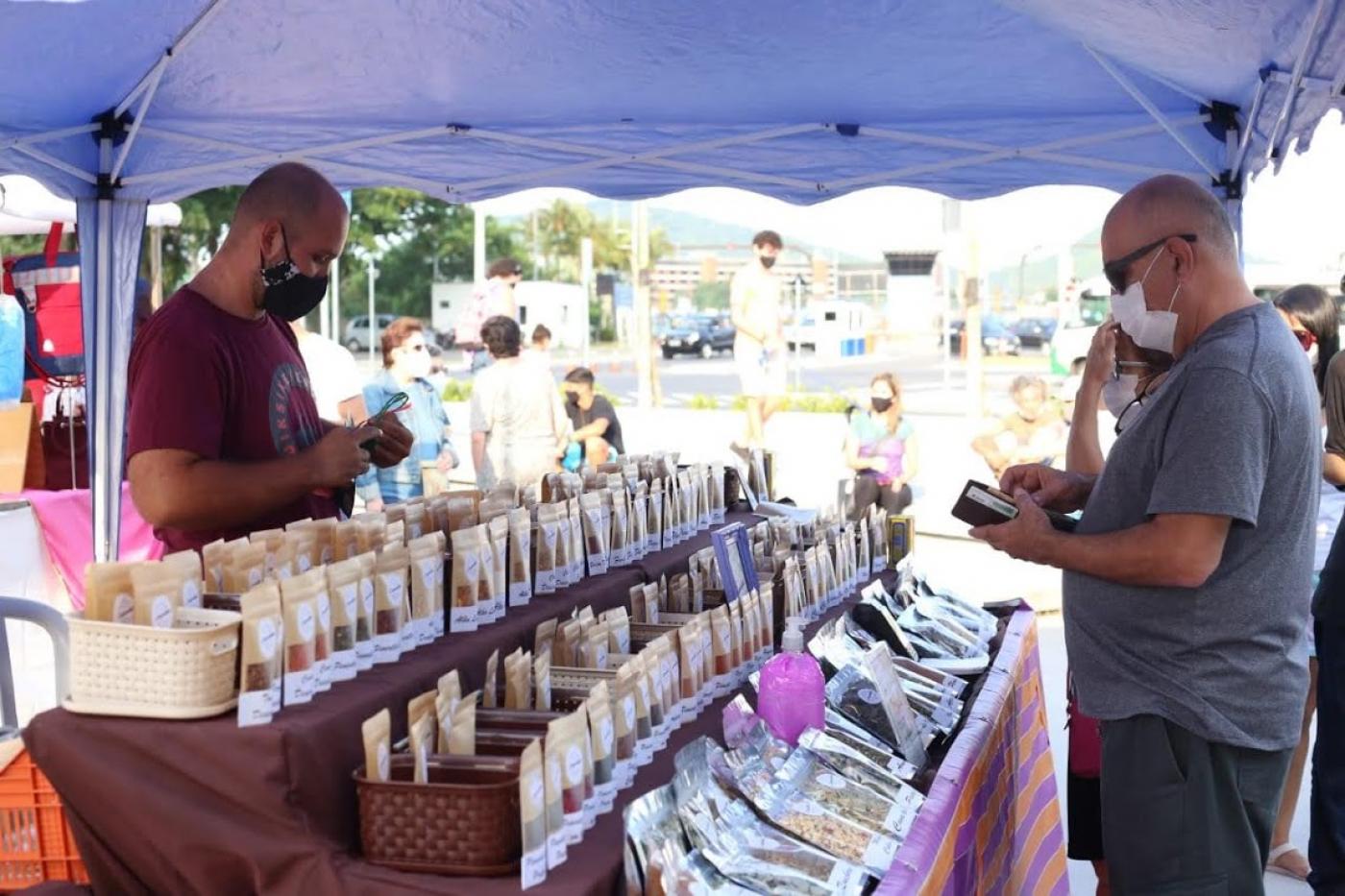 homem abre carteira para pagar por produto em barraca da feira #paratodosverem