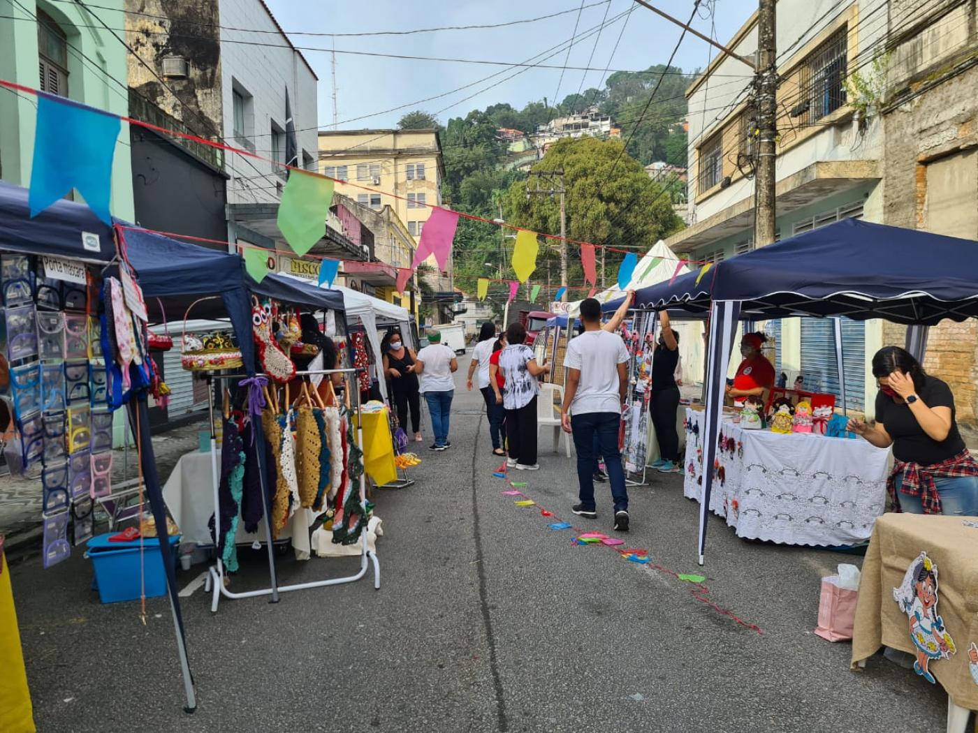 rua decorada com bandeirinhas e barracas nas laterais. #paratodosverem