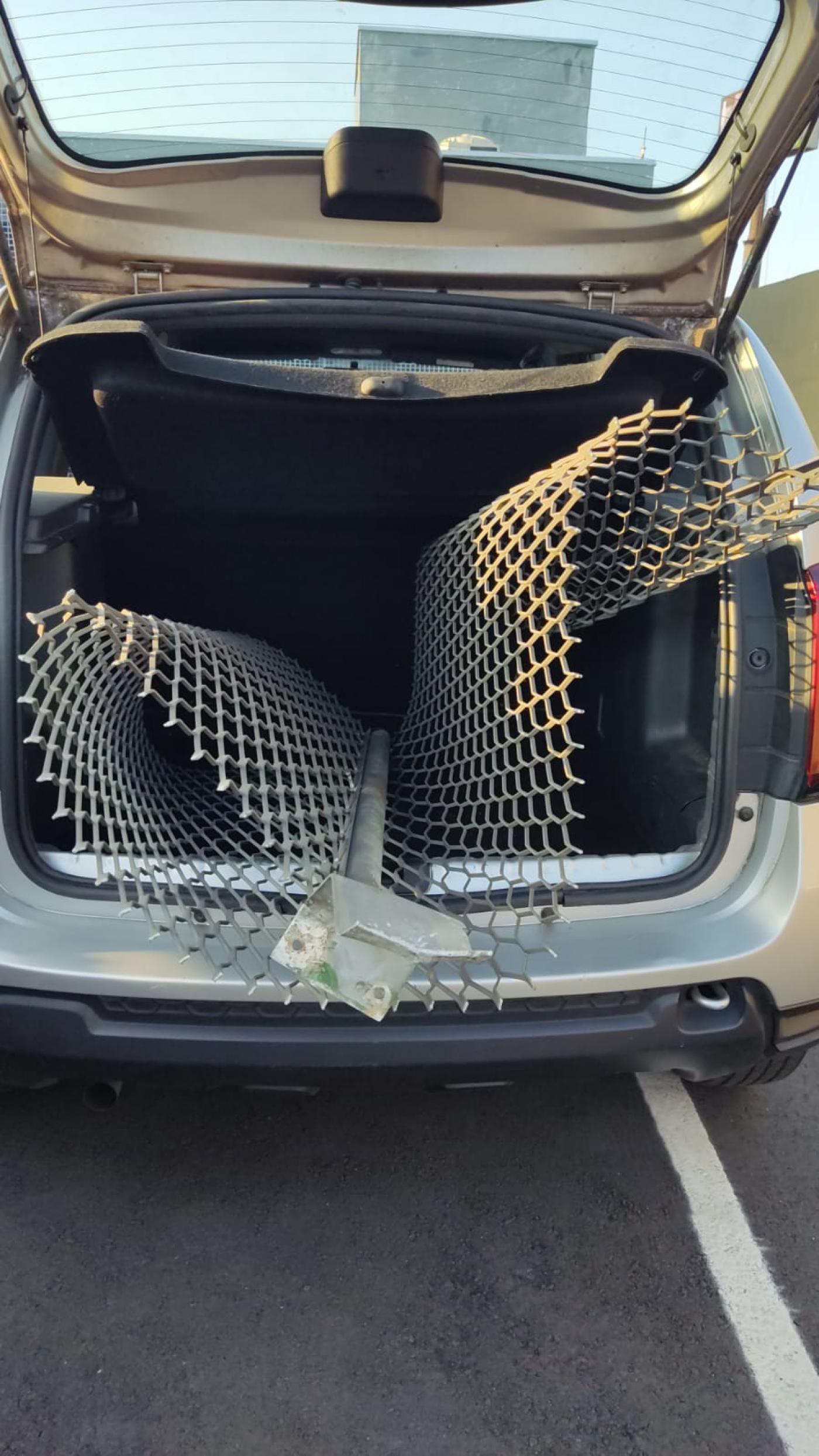 Porta mala do carro aberto com gradil de ferro dentro. #paratodosverem