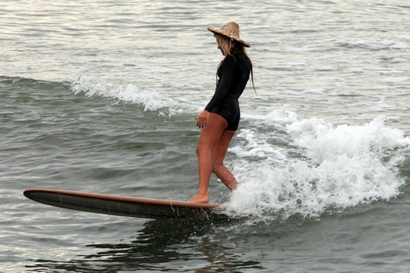 mulher em cima de prancha surfando #paratodosverem