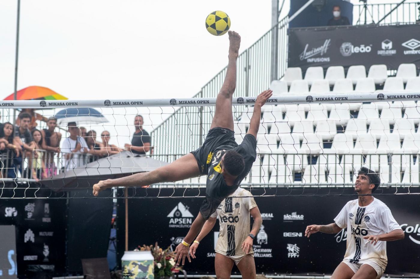 atleta dá salto para chutar a bola em jogo #paratodosverem