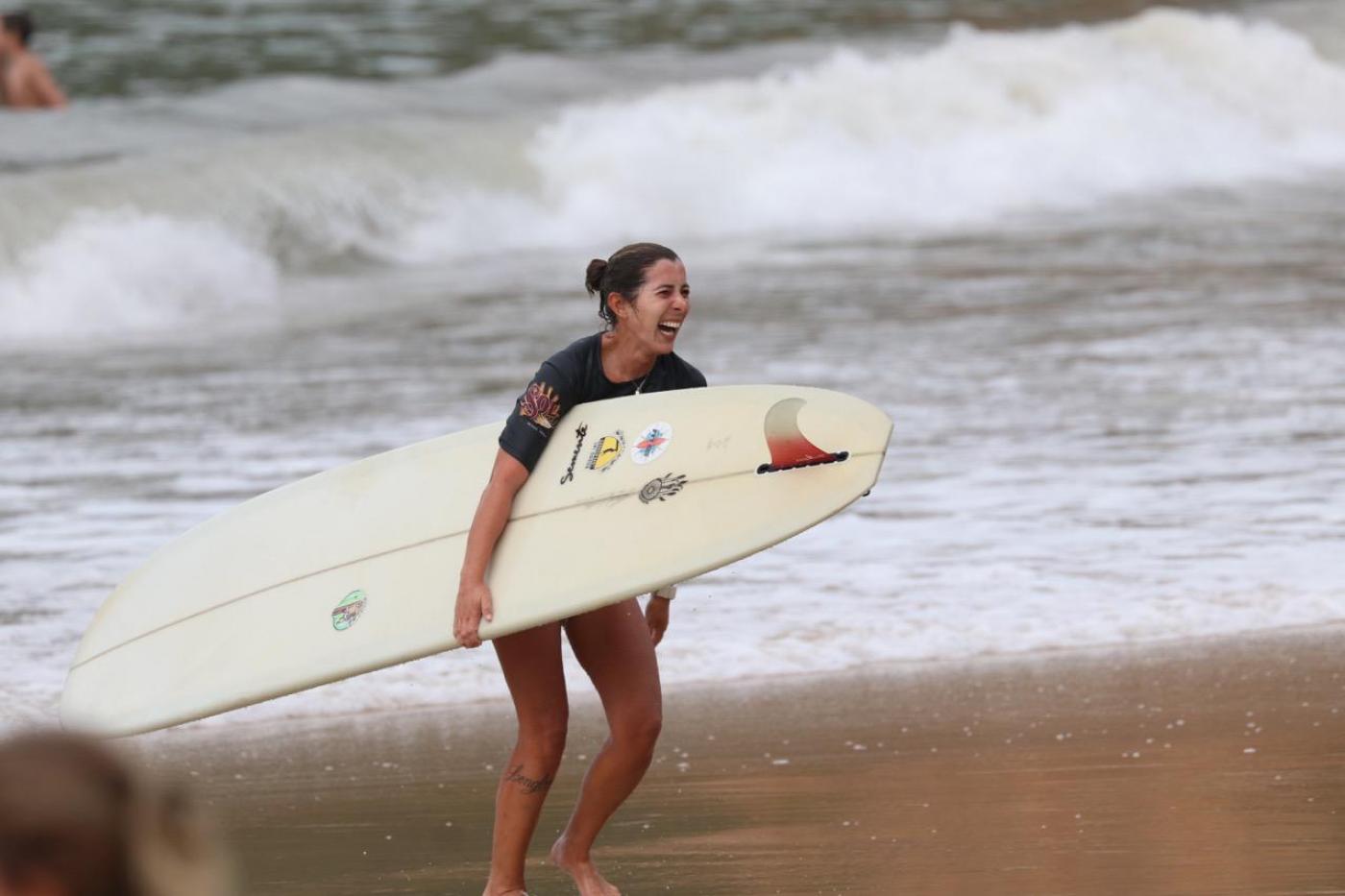 surfista com a prancha sai do mar sorrindo #paratodosverem