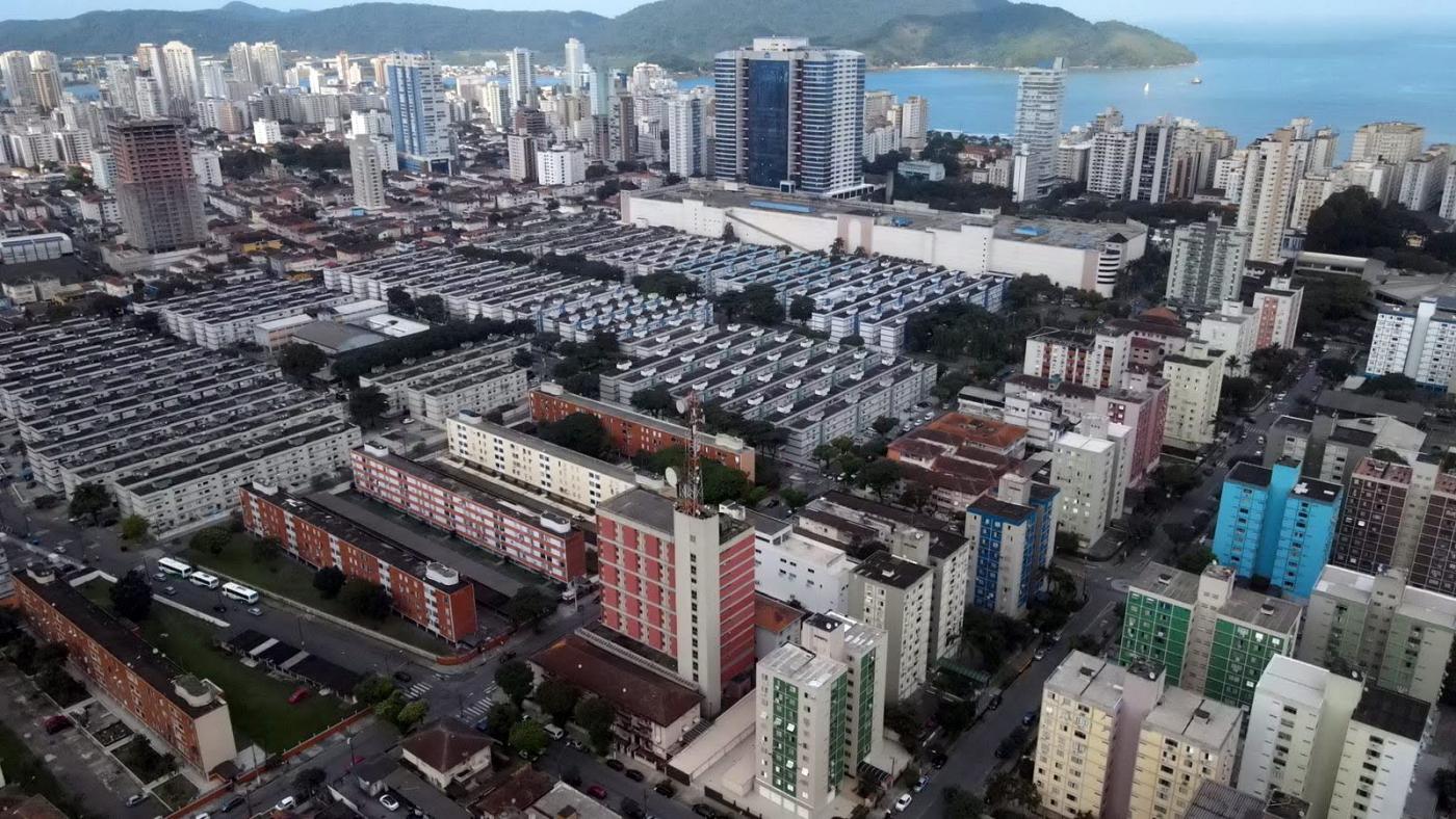 vista aérea de bairro com muitos prédios e o mar ao fundo. #paratodosverem 