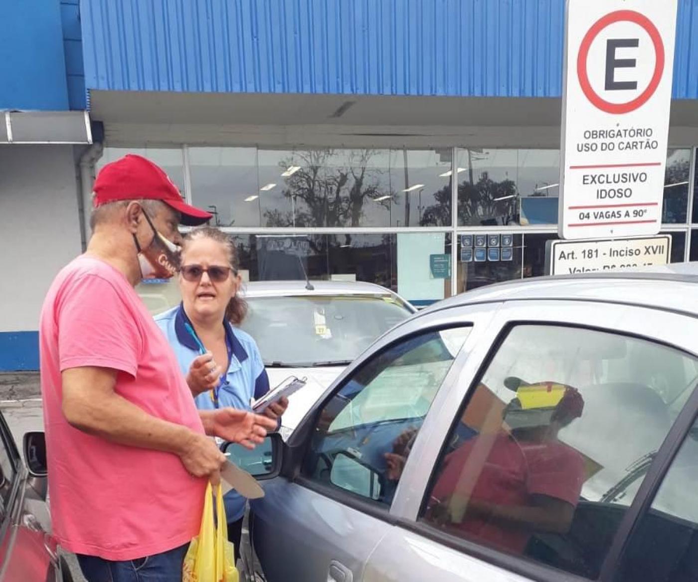 agente orienta homem ao lado de carro em estacionamento #paratodosverem