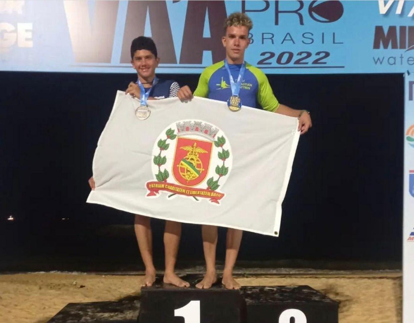 irmaos no pódio segurando a bandeira de Santos #paratodosverem