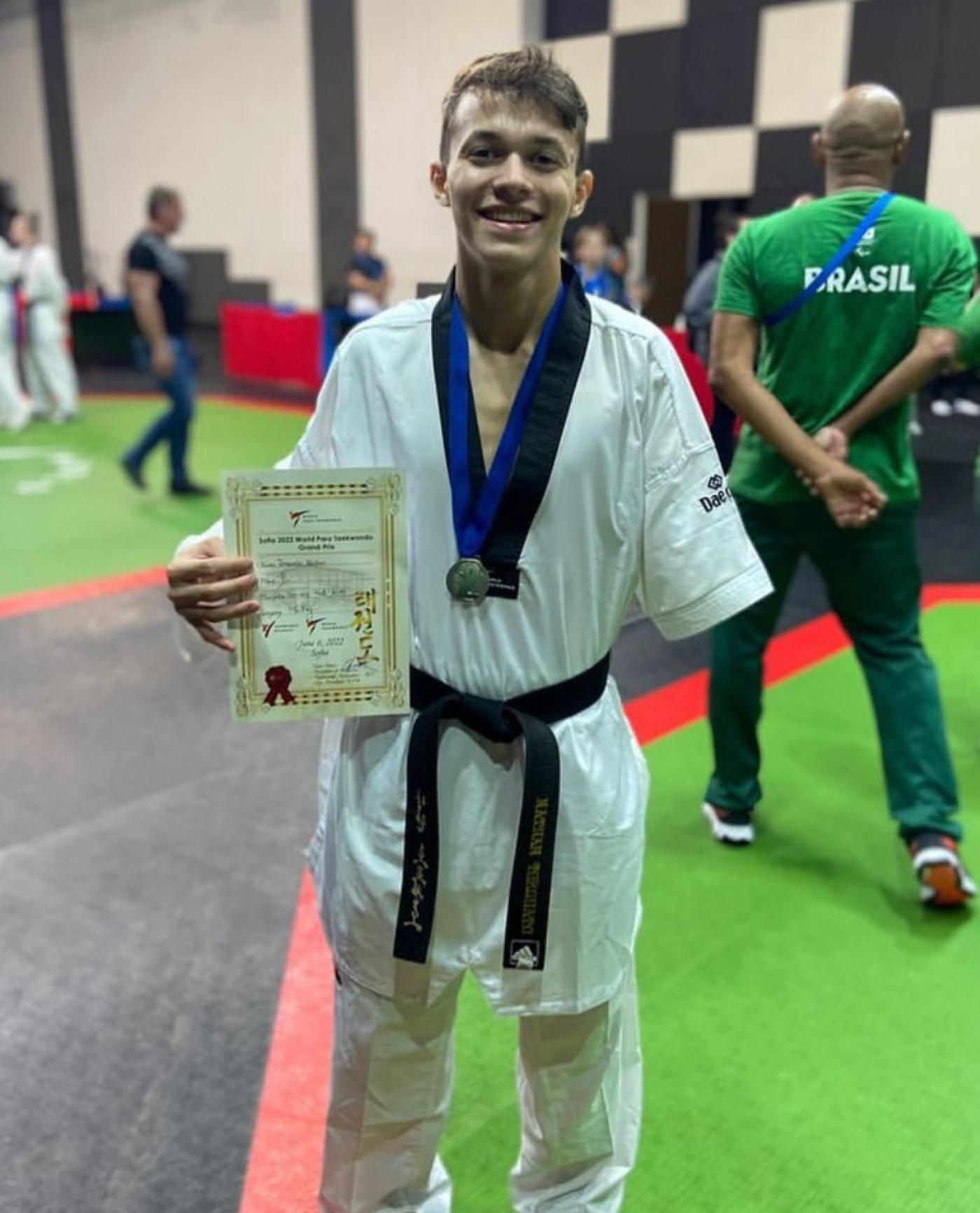 atleta de quimono exibe diploma e medalha #paratodosverem