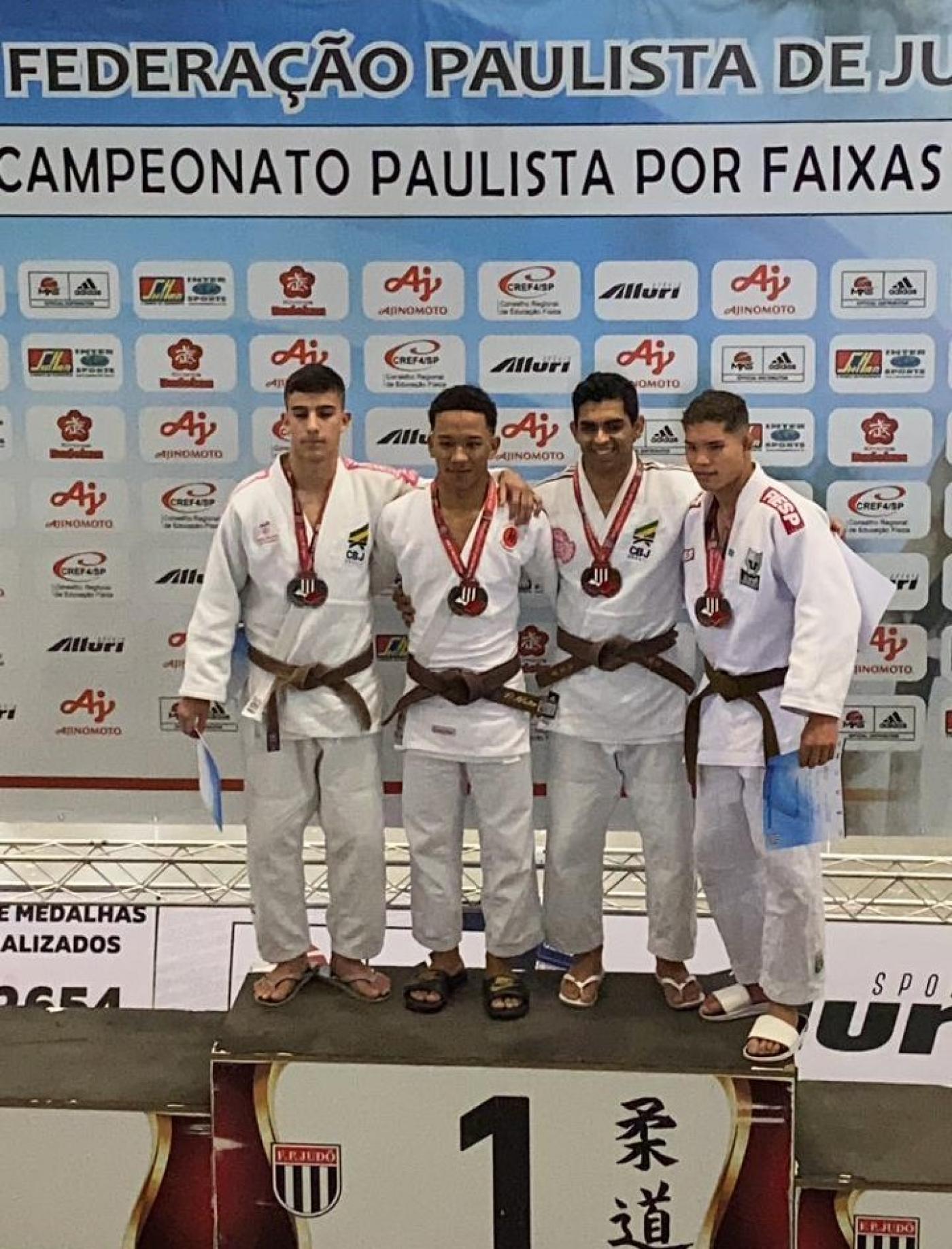 judocas no pódio com medalhas #paratodosverem