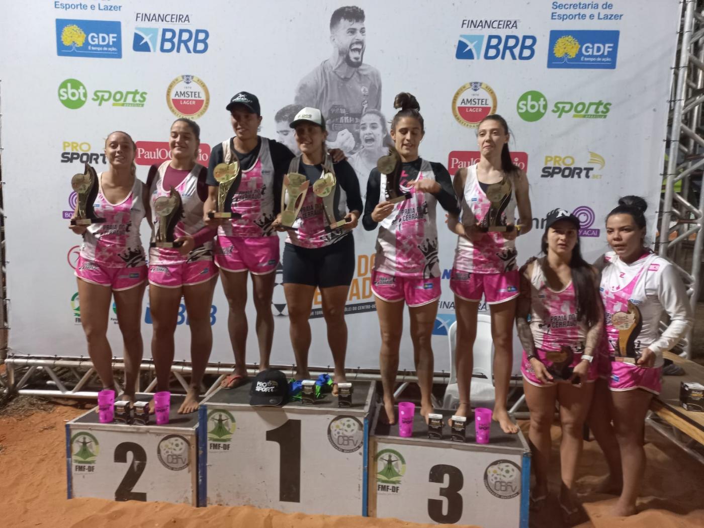 atletas no pódio seguram troféus #paratodosverem