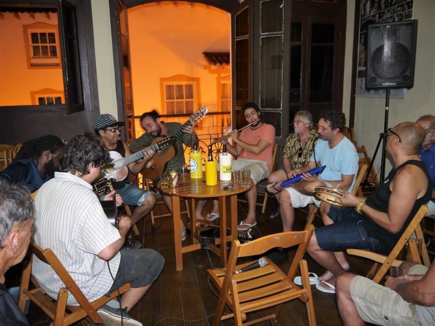 pessoas ao redor de mesa sentadas tocando instrumentos #paratodosverem