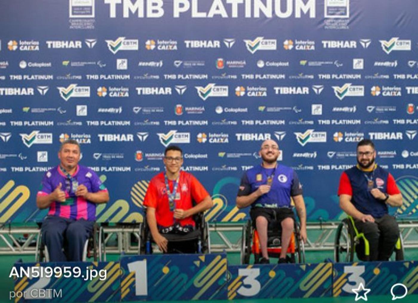 atletas cadeirantes com medalha atrás do pódio #paratodosverem