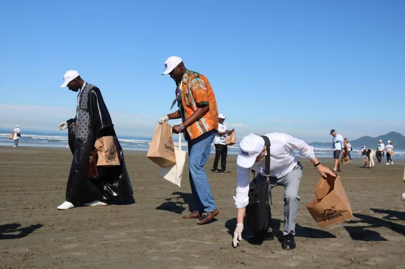 participantes da conferencia recolhem lixo na praia #paratodosverem