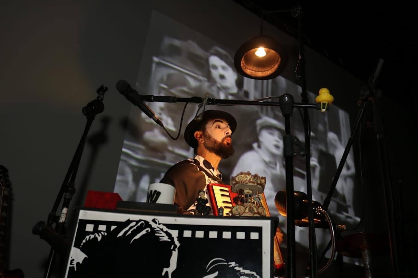 artista tocando no palco com filme sendo exibido ao fundo #paratodosverem