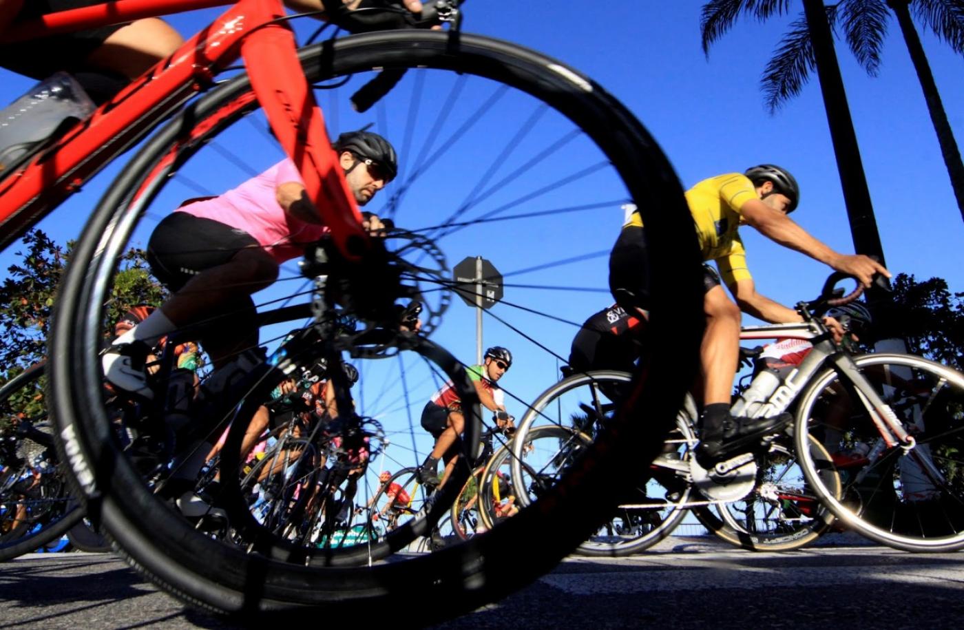 imagem de ciclistas pedalando com roda de bicicleta em primeiro plano #paratodosverem