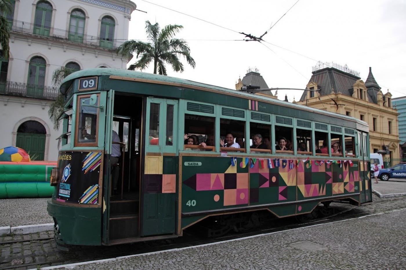 bonde com pessoas dentro circula por rua no centro histórico #paratodosverem