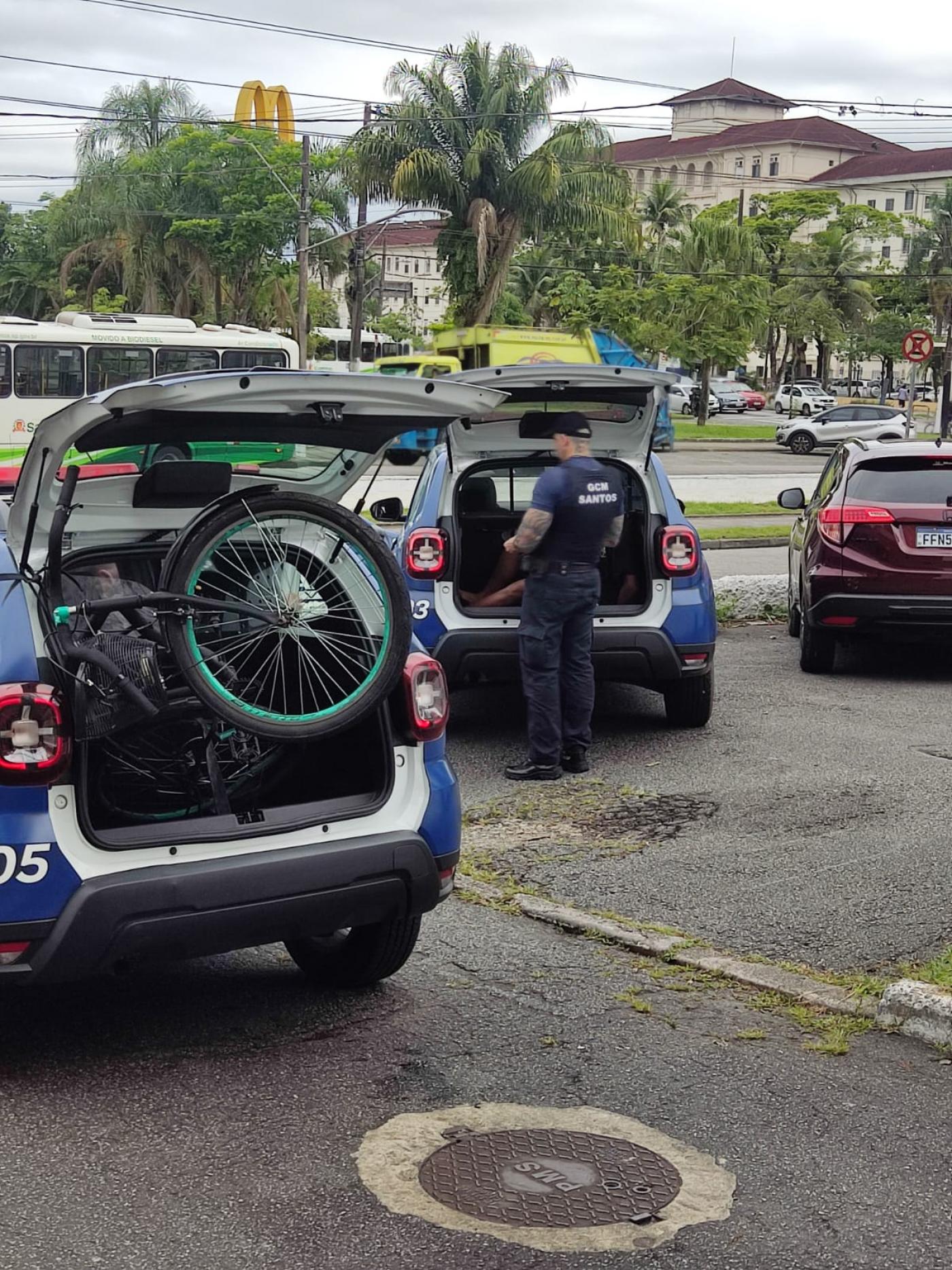 duas viaturas da guarda municipal, ambas com o capô aberto. Em uma delas há uma bicicleta. #paratodosverem