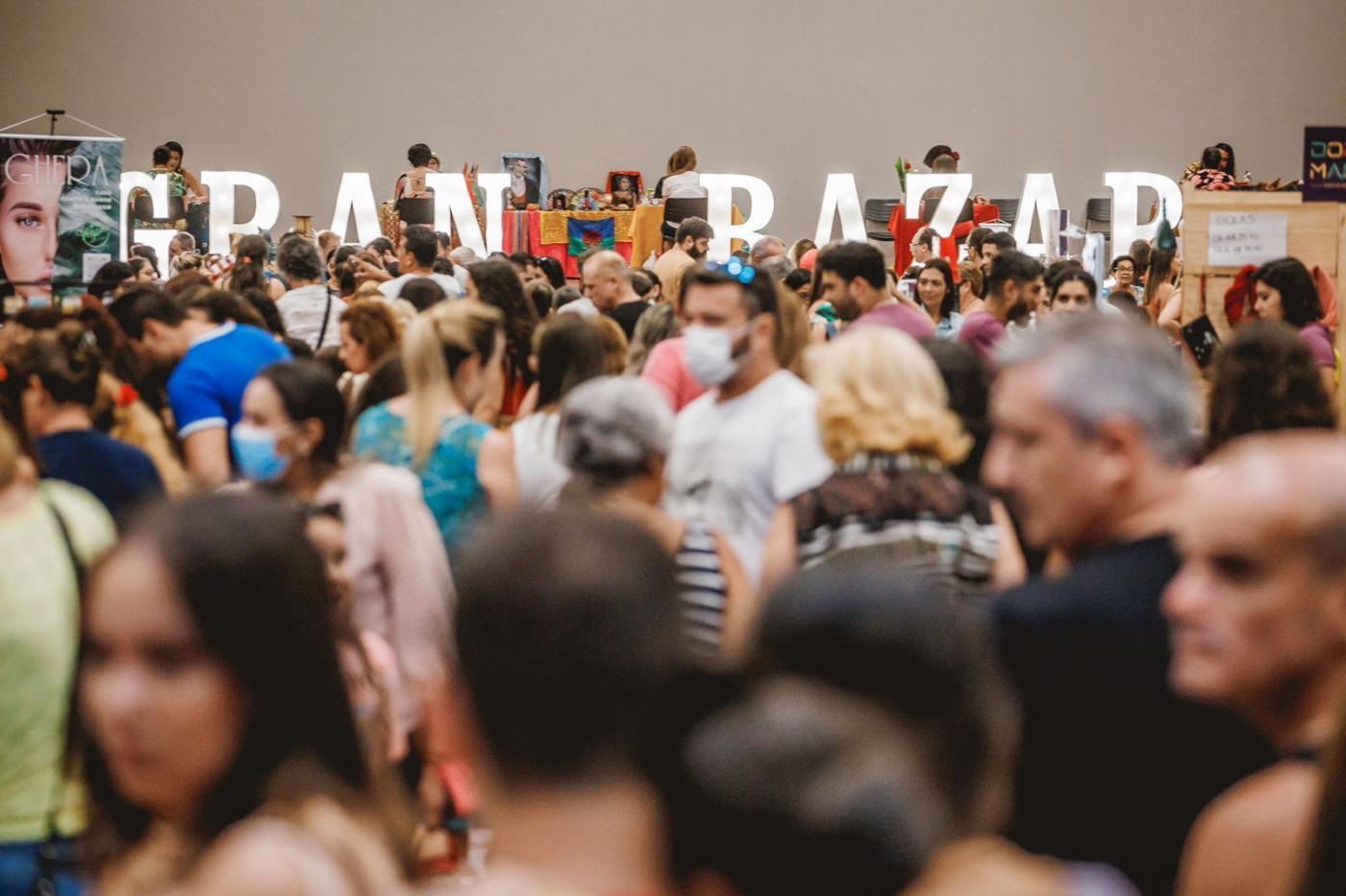 várias pessoas se movimentando dentro de um salão. Ao fundo se lê gran bazar. #paratodosverem