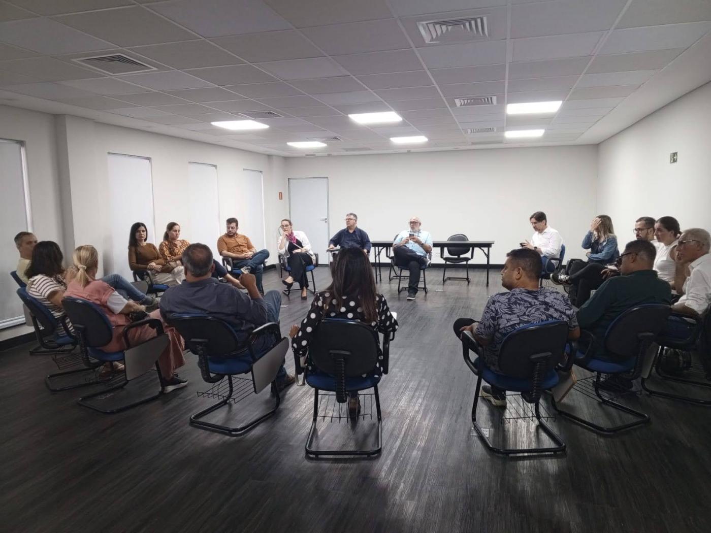 pessoas sentadas e reunidas em roda em salão. #paratodosverem 