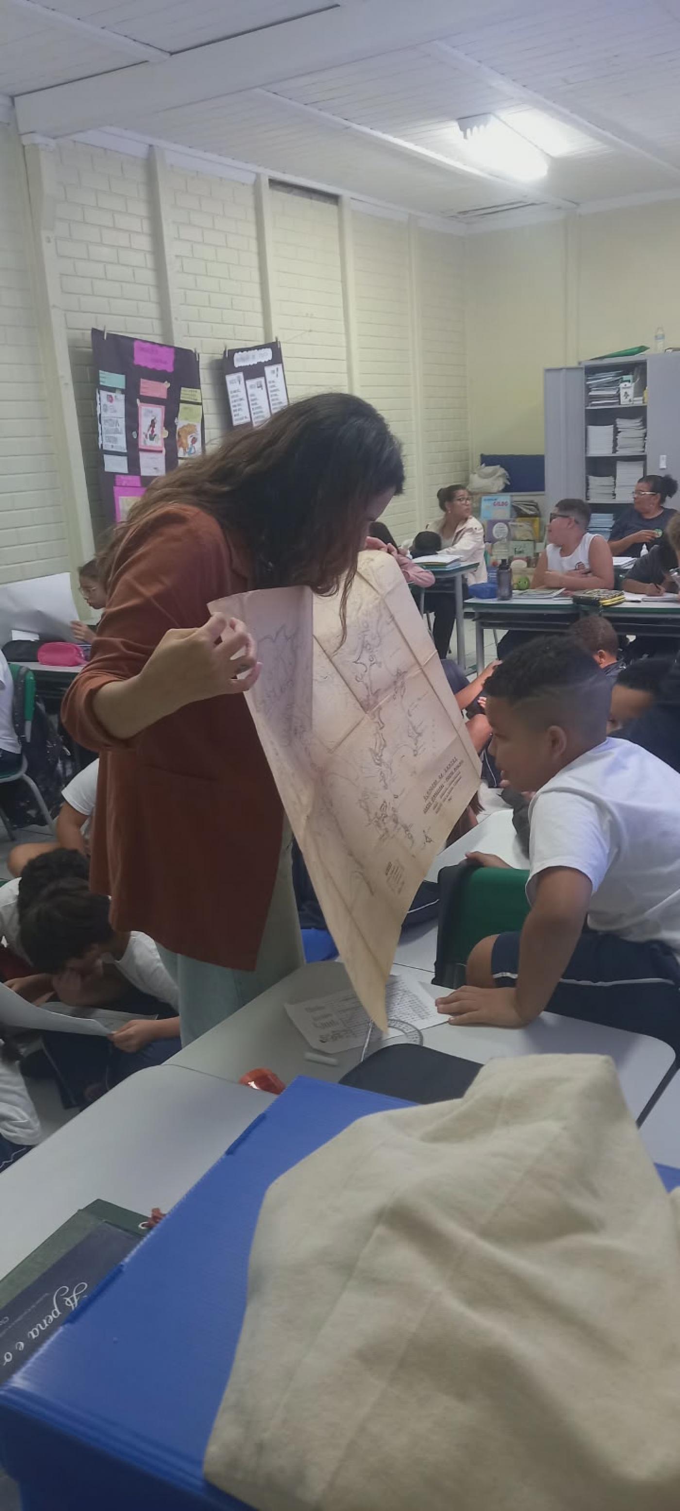 professora mostra mapa a aluno #paratodosverem
