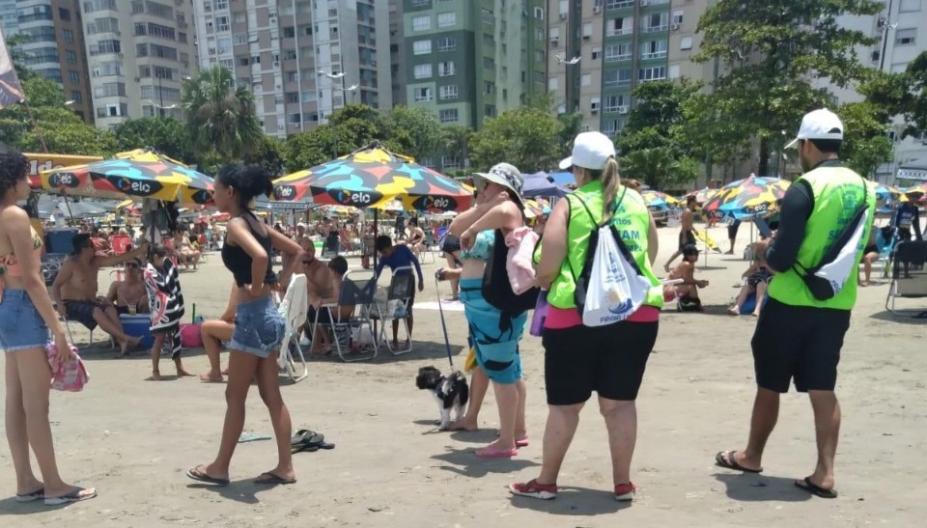 agentes uniformizados abordam mulher que está com cachorro na faixa de areia. #paratodosverem