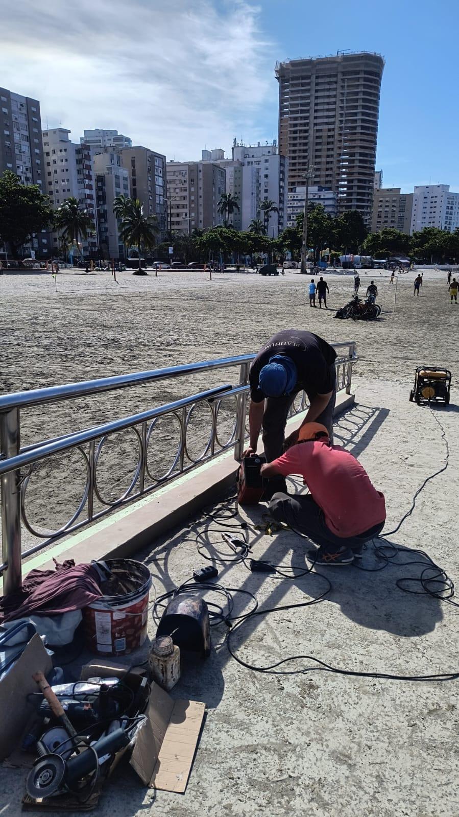 doois omens estão ao lado de guarda-corpo fazendo um reparo. #paratodosverem 