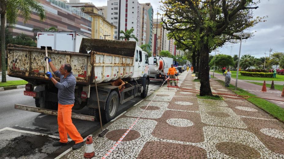 homens despejam detritos em caminhão estacionado na orla da praia. #paratodosverem 