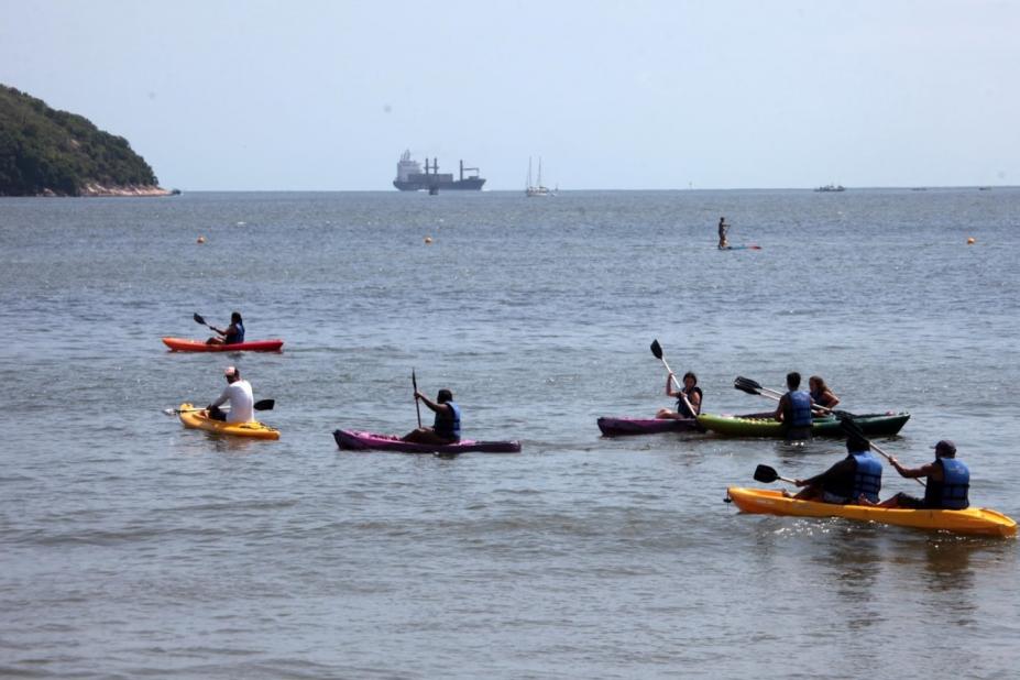 No mar, várias pessoas praticando canoagem. #paratodosverem