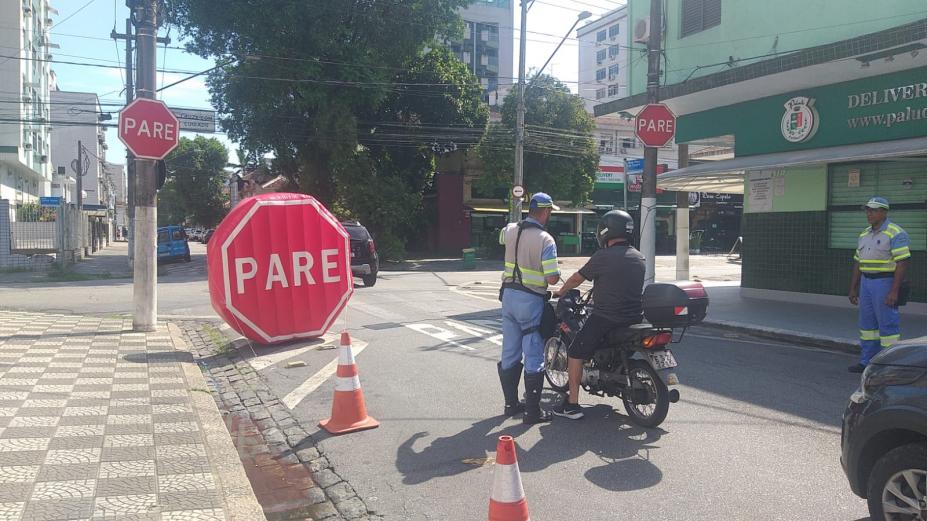 agente da CET aborda motociclista no meio da rua. à frente há um grande inflável onde se lê Pare. #paratodosverem