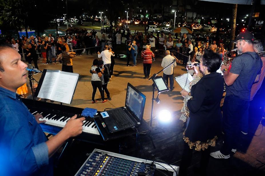 músicos tocando e pessoas dançando ao fundo #paratodosverem