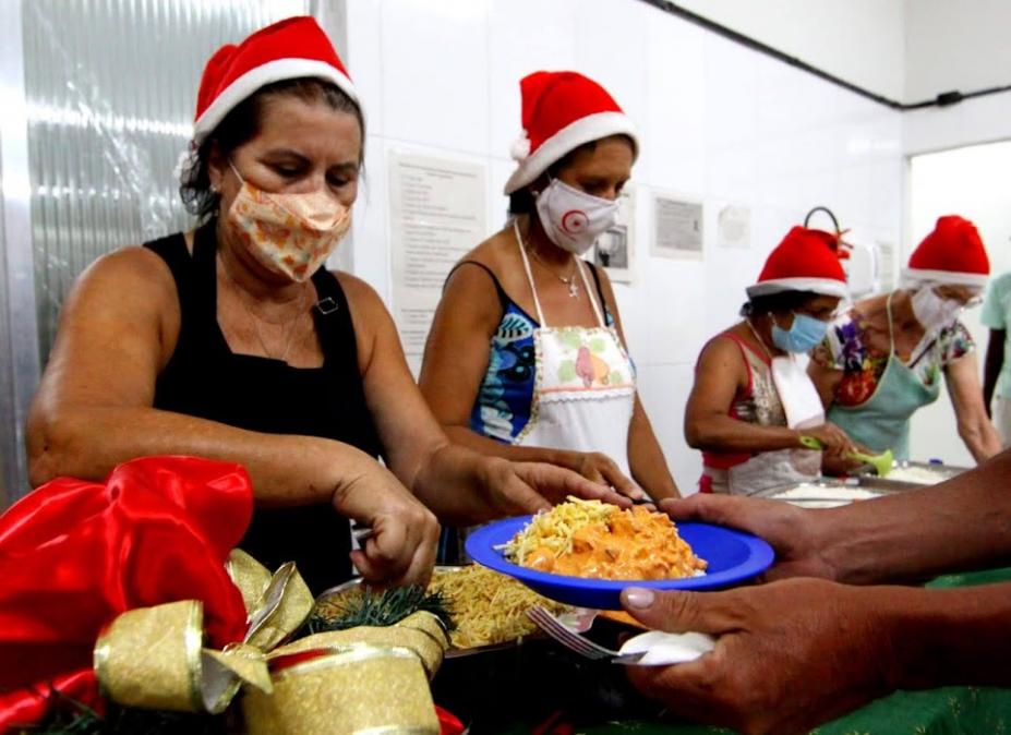 voluntários com toca de papai noel servem comida #paratodosverem