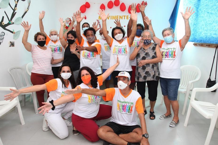 mulheres estão reunidas em unidade de saúde. Elas posam para foto com os braços abertos. #paratodosverem
