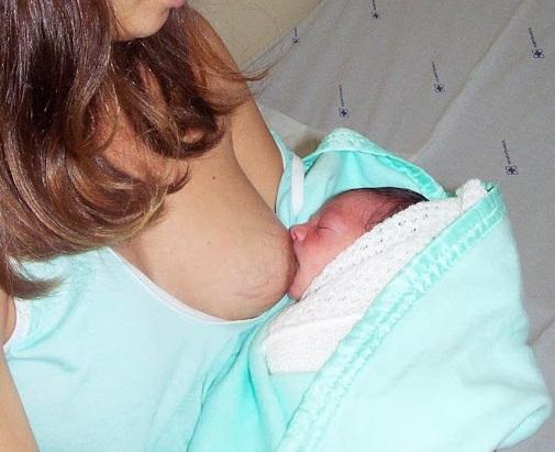 Bebê é amamentado no peito. #paratodosverem