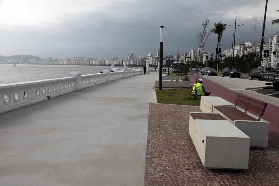 Trecho da orla remodelado, com bancos ao lado direito, calçadão, mureta e o mar. #Pracegover