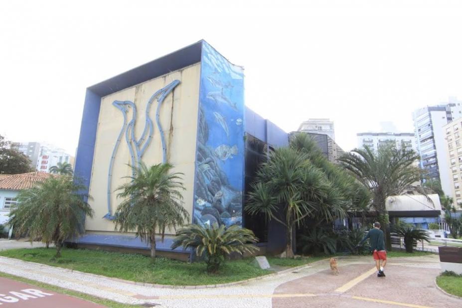 fachada lateral do parque com ilustração em relevo de dois pinguins em uma face e uma arte sobre o oceano na empena direita. #paratodosverem