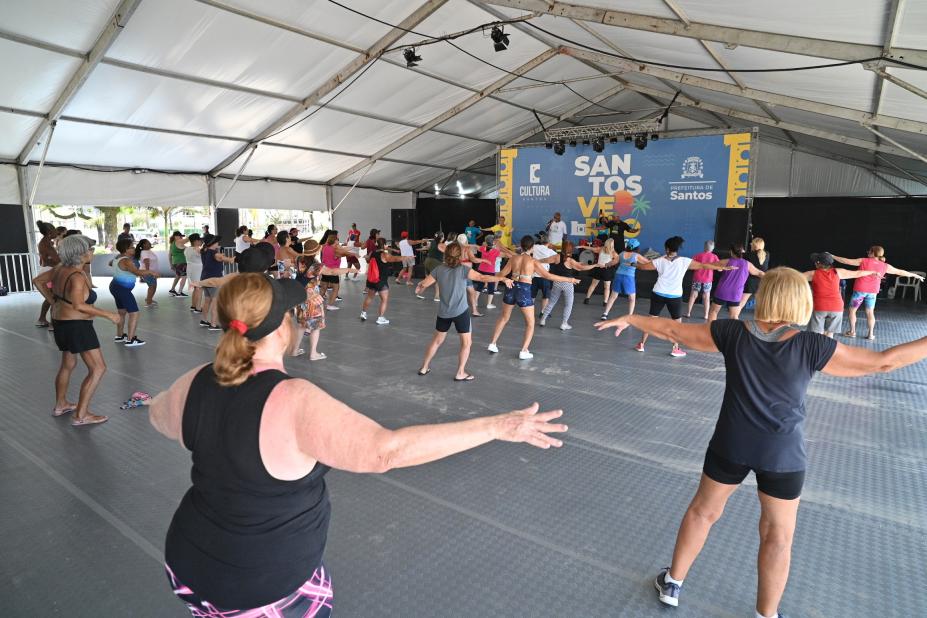 mulheres fazem alongamento sob tenda. #paratodosverem