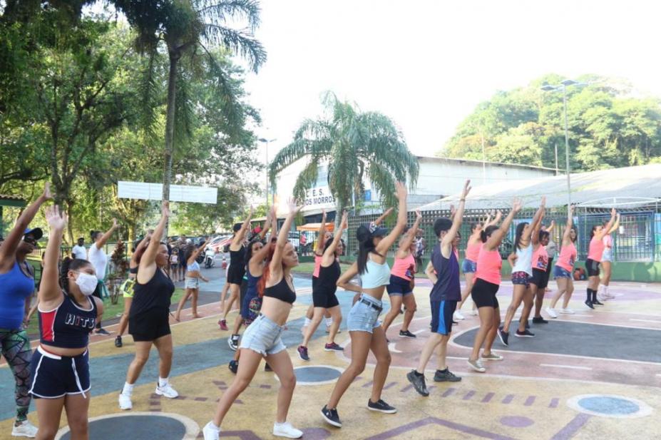 mulheres fazem movimentos iguais de dança em praça. #pratodosverem