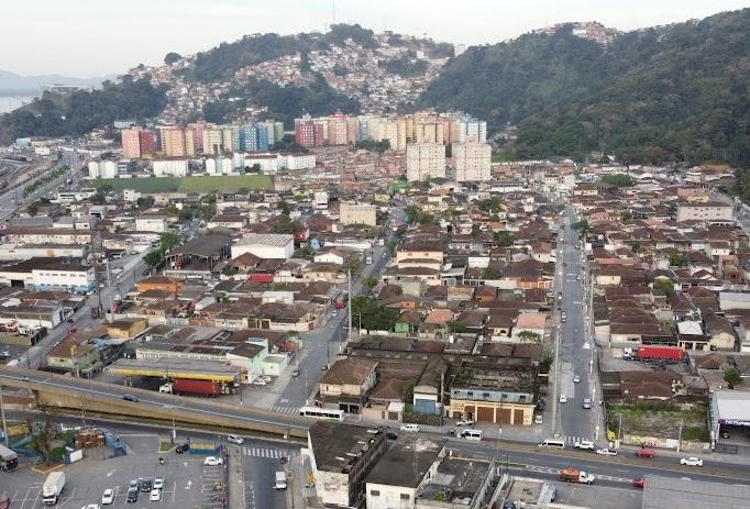 vista geral de bairro com diversas construções e morro ao fundo. #paratodosverem