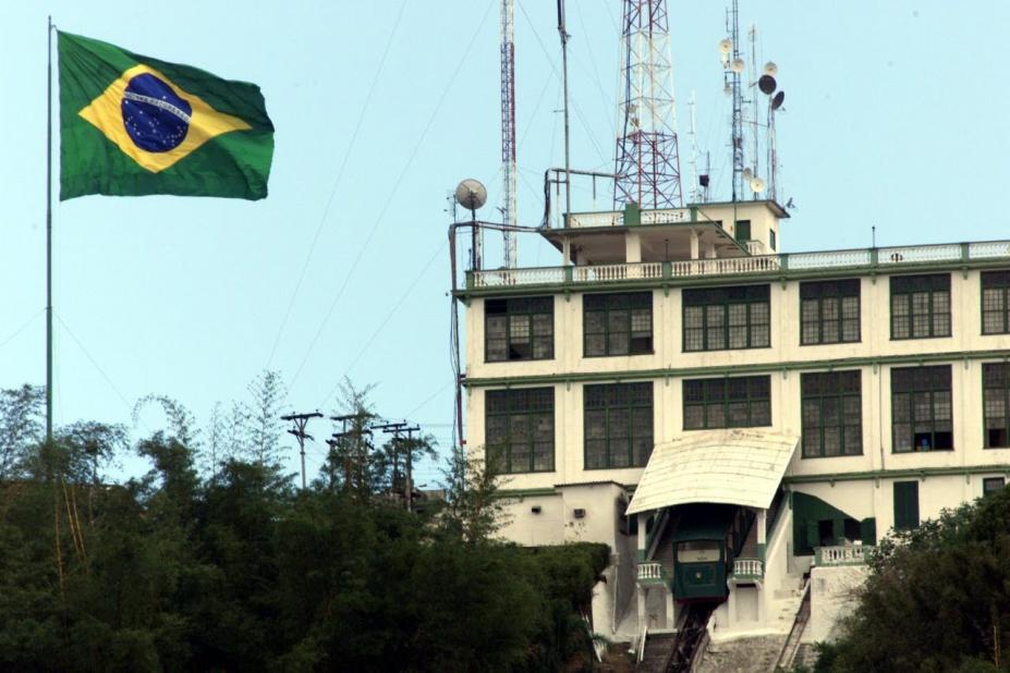 A bandeira do brasil hasteada com o prédio do antigo cassino do Monte Serrat ao lado. #Paratodosverem