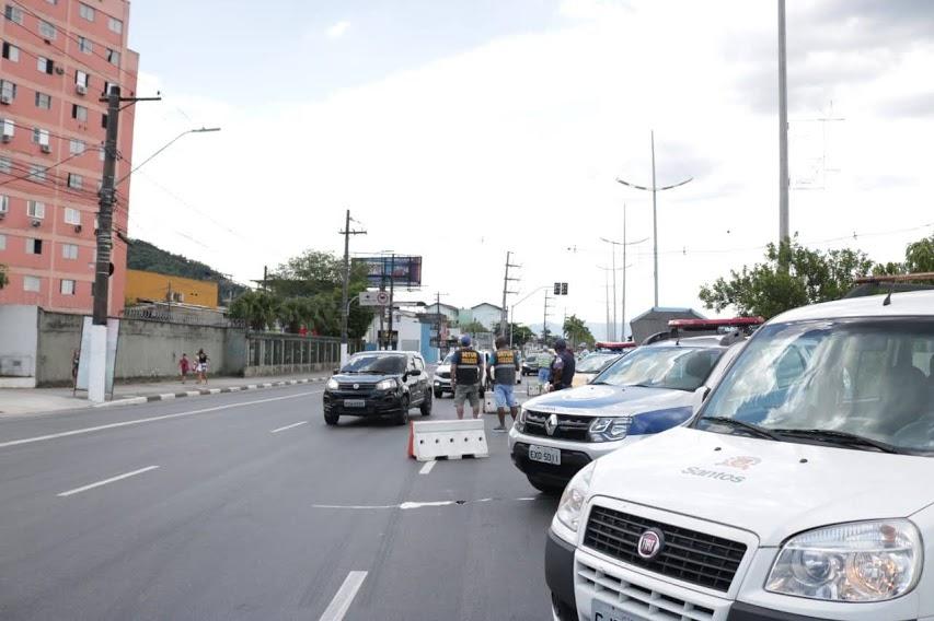 Veículos estacionados com fiscais, de costas, observando o fluxo de veículos na barreira montada no Saboó. #pracegover