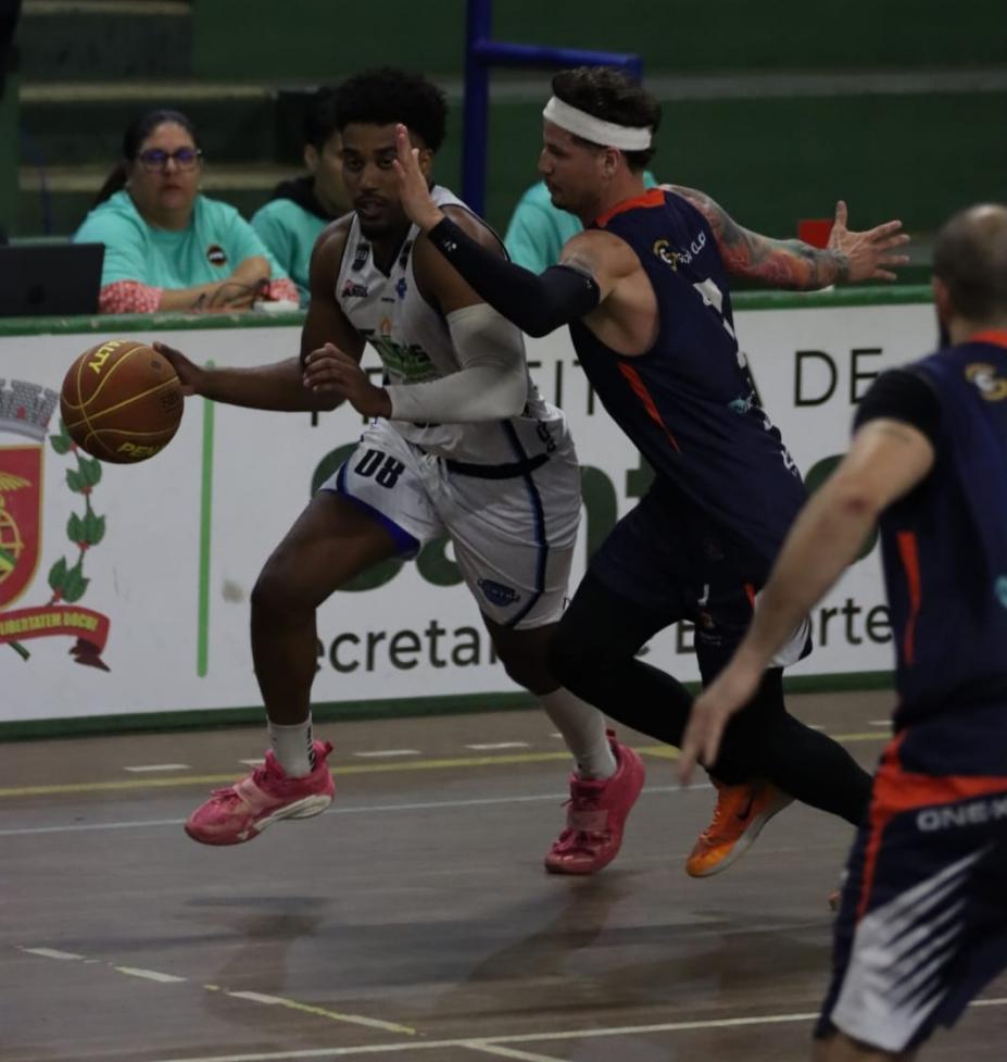 Jogadores de basquete disputando partida. #Paratodosverem.