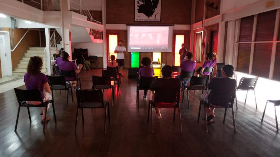 jovens estão em auditório assistindo a projeção. #paratodosverem