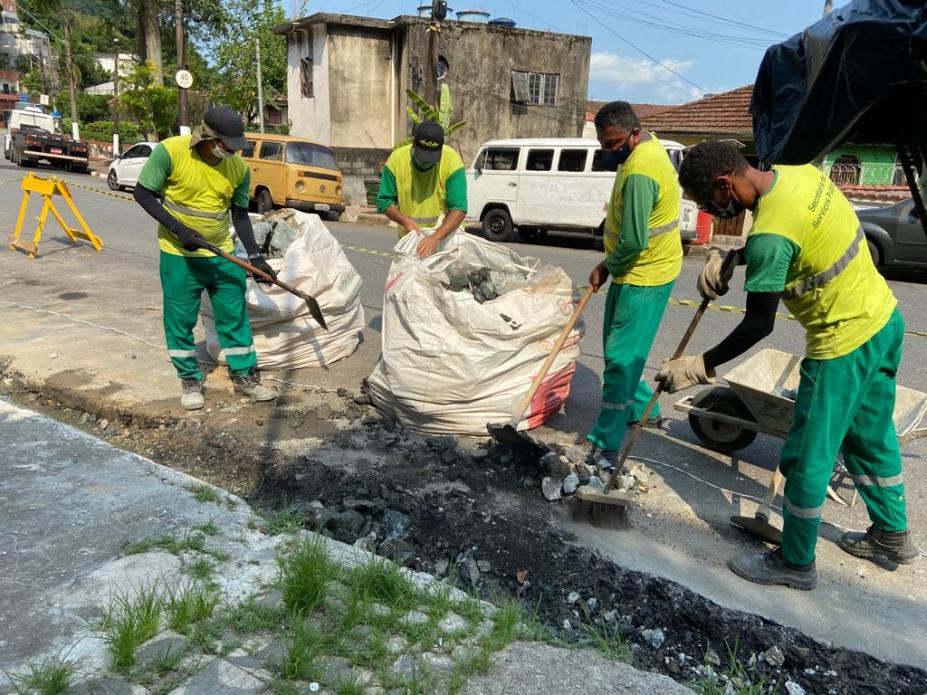 quatro homens escavam e limpam canaleta aberta para bueiros. #paratodosverem