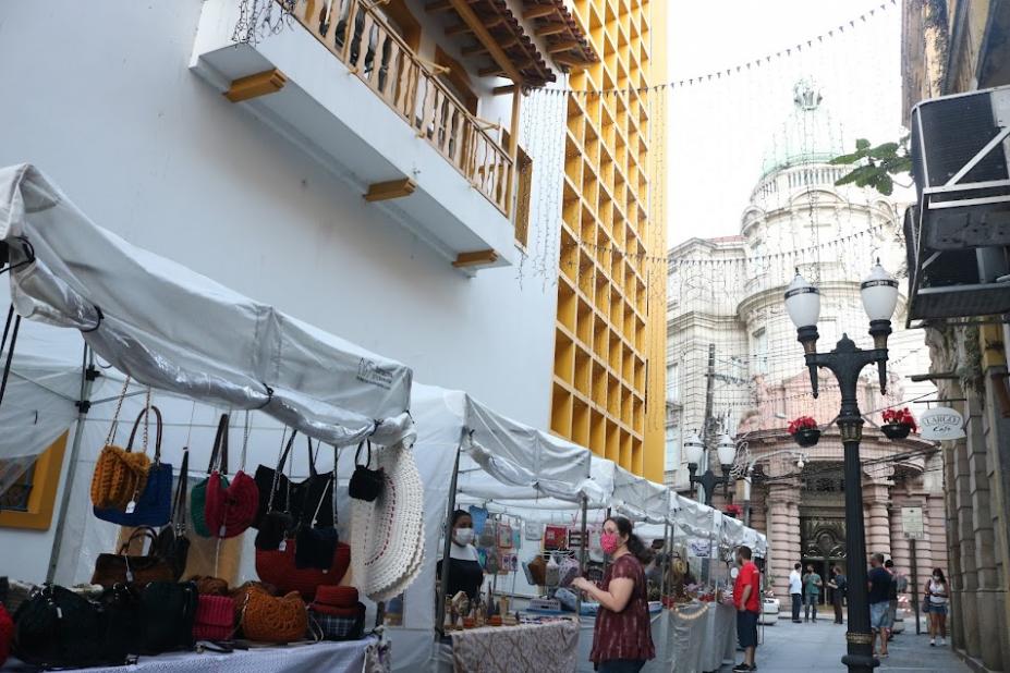 barracas de artesanato estão montadas em rua. #paratodosverem