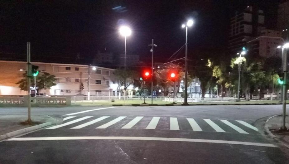 Imagem da via a noite com faixa de pedestre em primeiro plano #paratodosverem